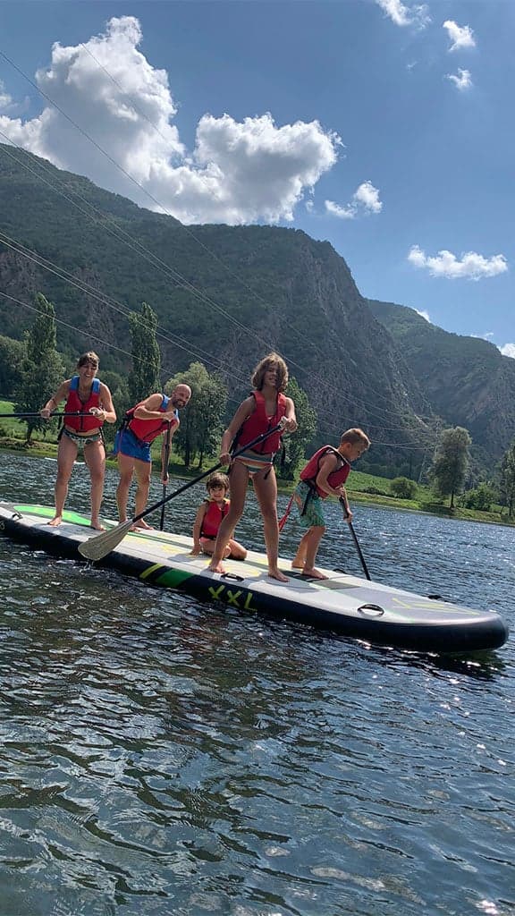 Group of people coordinating to paddle on a giant Big SUP board at La Torrassa Lake.